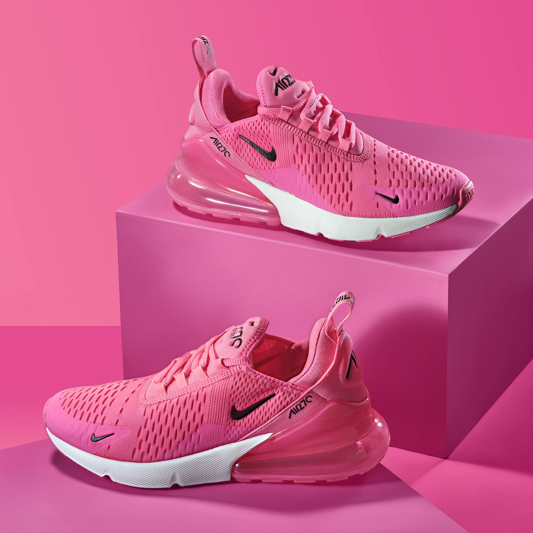 Studio product photography of pink Nike Air Max 270 trainers displayed on geometric plinths.
