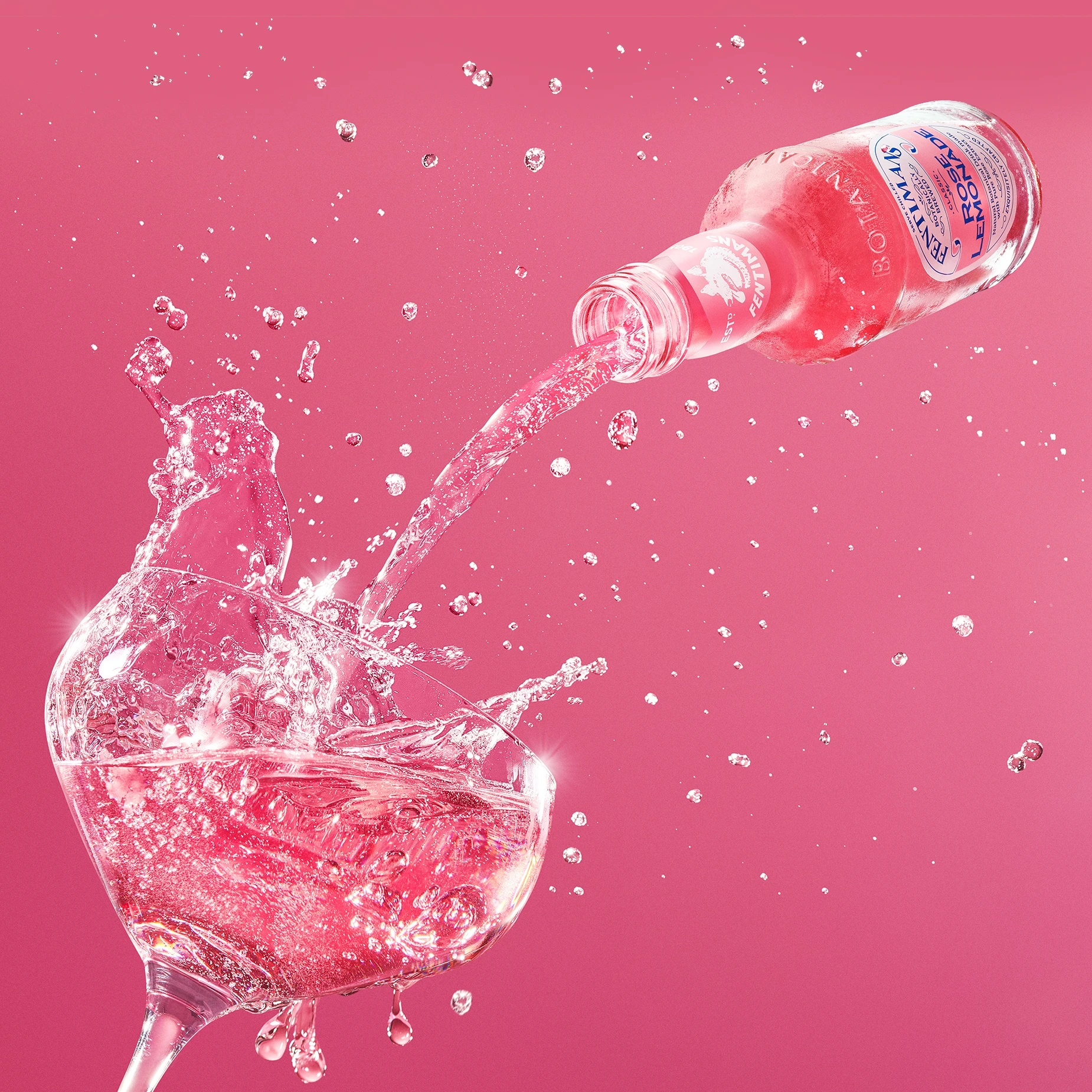 Commercial product photography of Franklin & Sons rose lemonade pouring into a glass against a pink background.